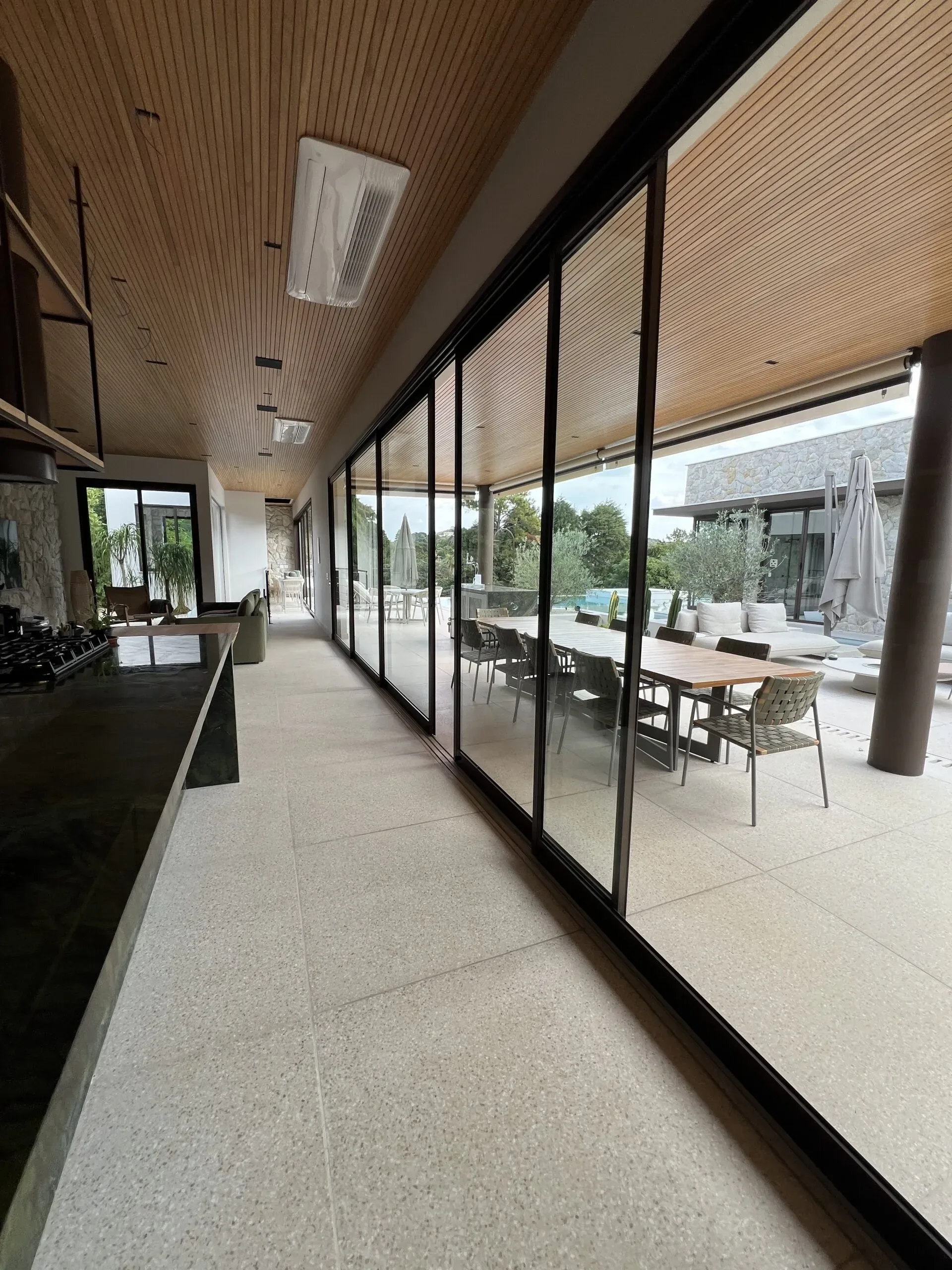 Portas de correr de esquadria preta integrando área gourmet ao jardim