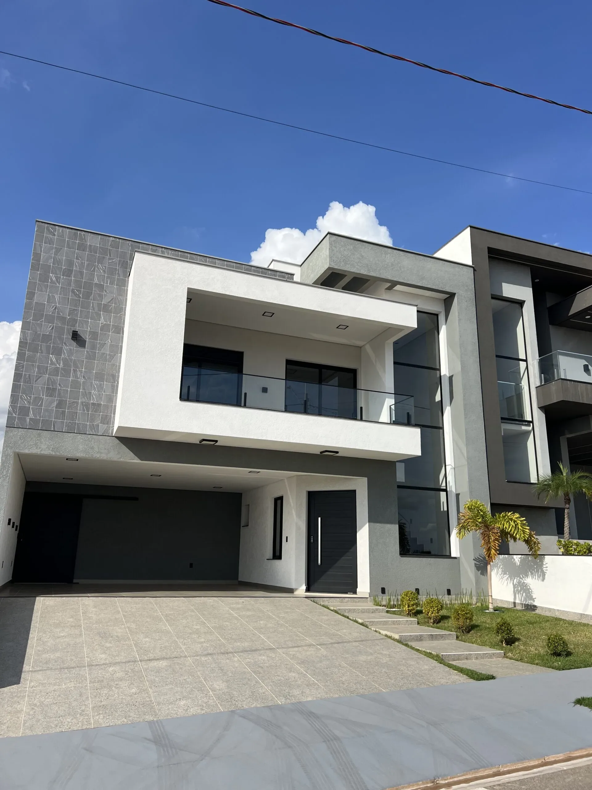 Fachada residencial com sacada superior protegida por fechamento de vidro