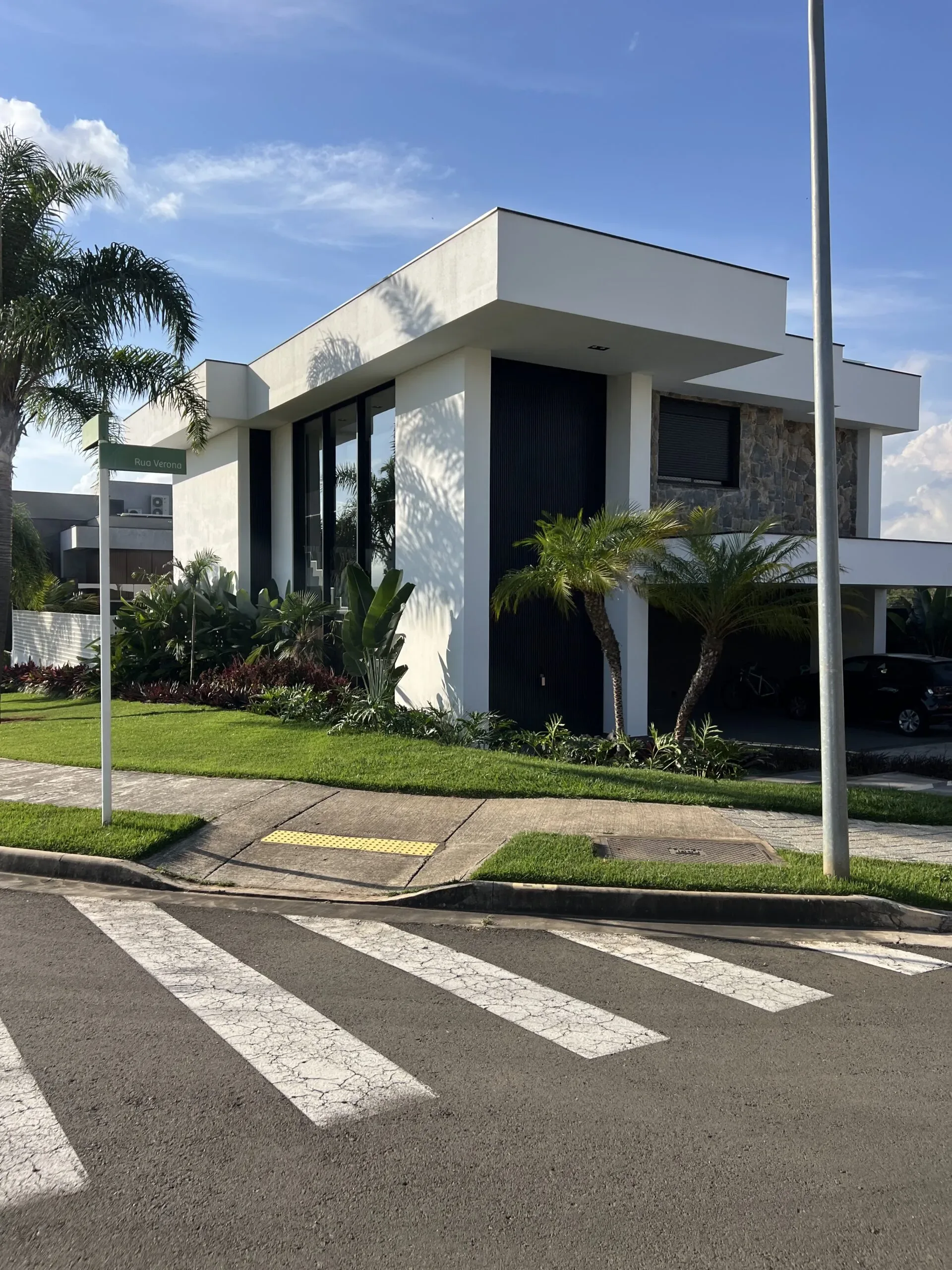 Varanda superior com brises verticais de alumínio e guarda-corpo de vidro em casa moderna