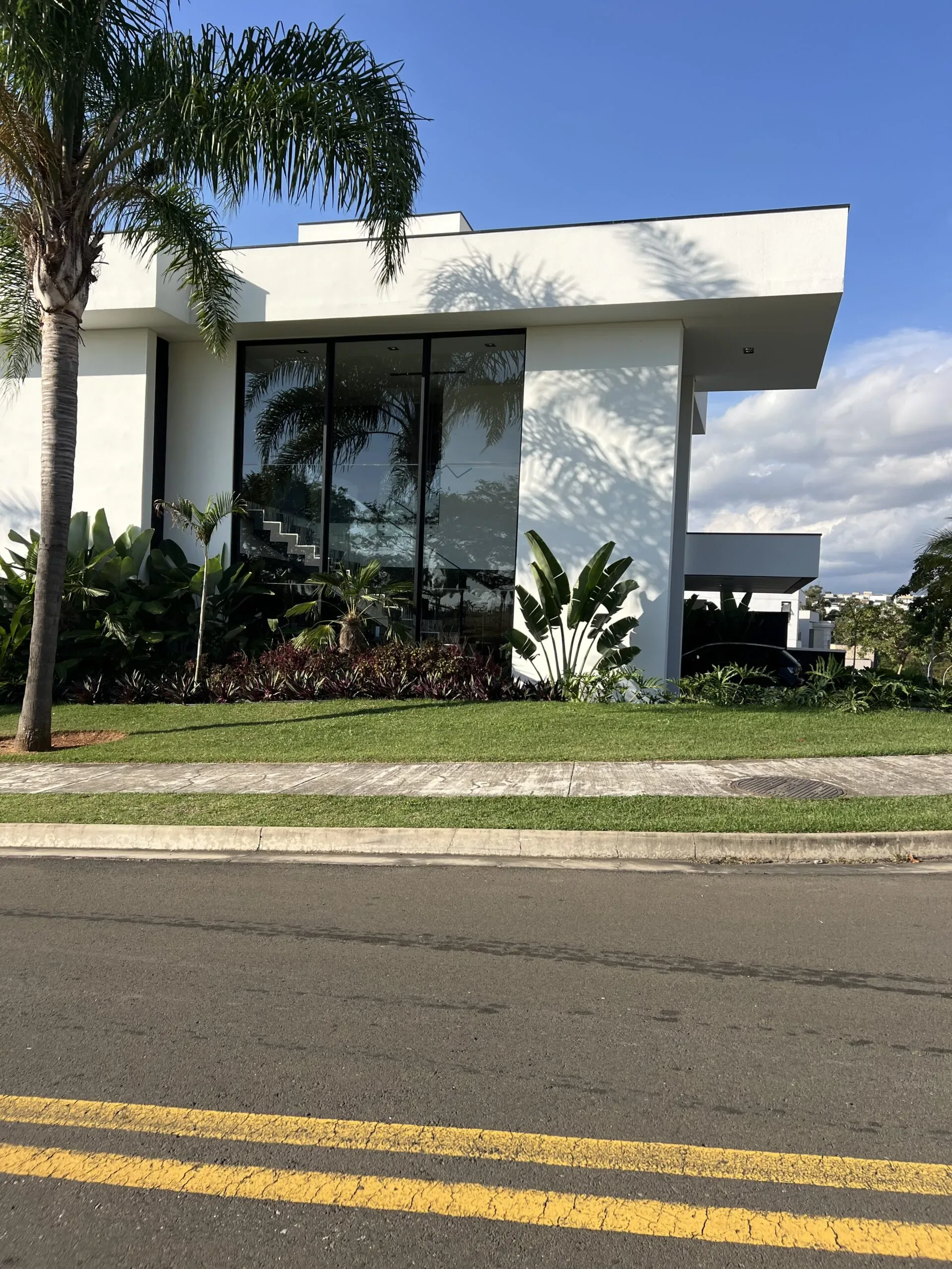 Fachada contemporânea com guarda-corpo de vidro e alumínio na varanda e brises verticais